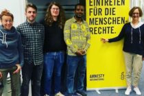 Organisator:innen und Dan vor einem Amnesty Banner